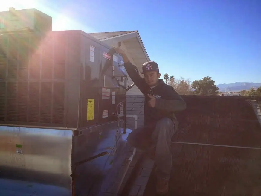 HVAC technician performing AC Tune-Up on a rooftop unit in St. Andrews